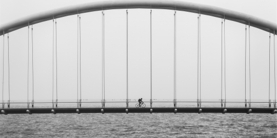 Brug over het water met een fietser in het midden.