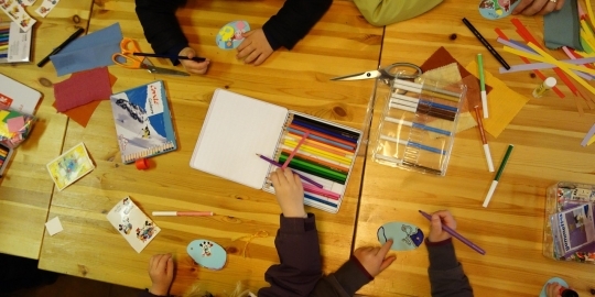 Kinderen aan tafel met knutselspullen van bovenaf